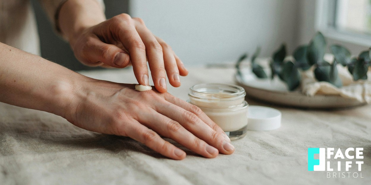 Photorealistic close-up of a person’s hands smoothing a small amount of unbranded moisturiser onto the back of one hand in warm natural daylight, conveying gentle aftercare and sun protection