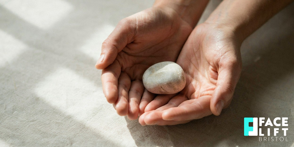 Close-up of a person’s hands cradling a smooth rounded stone in warm natural daylight, evoking restored structure and calm reassurance