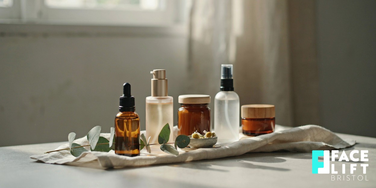 Still-life of several small unbranded amber and frosted-glass skincare bottles arranged in a graduated row on soft linen in warm daylight, symbolising layered complementary treatments