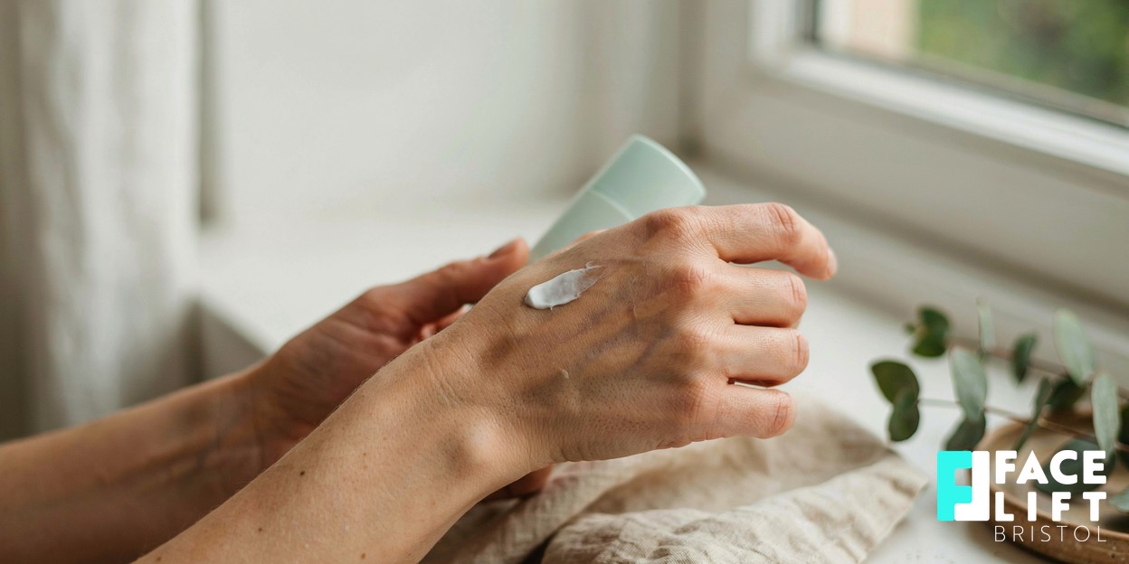 Close-up of a person’s hands applying a dab of white sunscreen along a forearm in soft natural daylight, conveying an everyday sun-protection habit